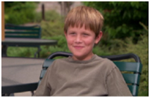 Boy sitting in a chair outside.