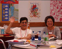 women sitting at a table, one waving